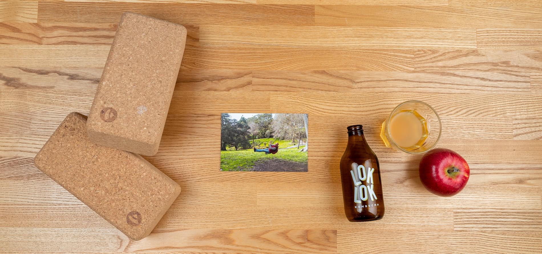 Korkový blok na jógu, fotografie, láhev a sklenice s kombuchou, jablko